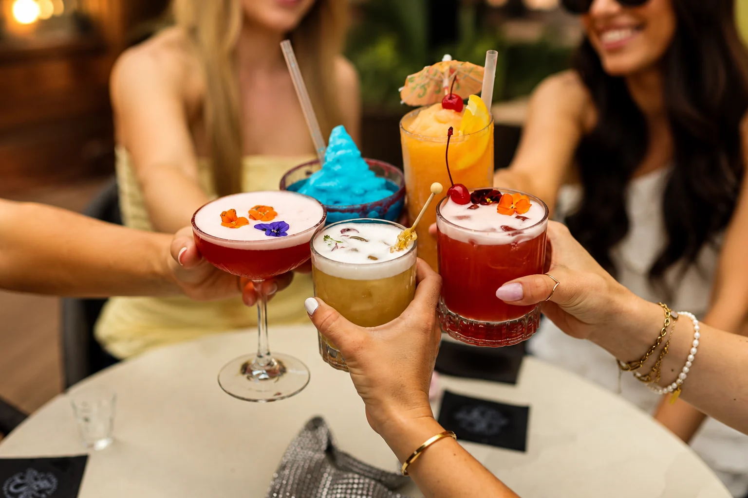 Friends raising colourful cocktails at Sunsets and Mermaids
